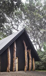 Eine kleine Kapelle aus dunklem Holz umgeben von Bäumen | © Alessandra Chemollo