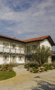 A two-storey house with a red tiled roof, painted white façade and light green shutters | © Alessandro Santi