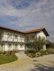 A two-storey house with a red tiled roof, painted white façade and light green shutters | © Alessandro Santi