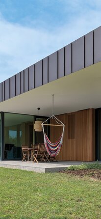 Una casa a un piano con ampie superfici vetrate, rivestimento in legno delle pareti e grande sporgenza del tetto piano | © Matteo Piazza