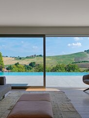 Ausblick aus einem Wohnzimmer auf einen Swimmingpoos und grüne Hügel | © Matteo Piazza