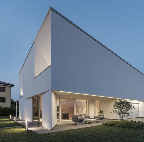 Eine moderne Villa mit verputzter Außenfassade und großen Fensteröffnung | © Davide Perbellini