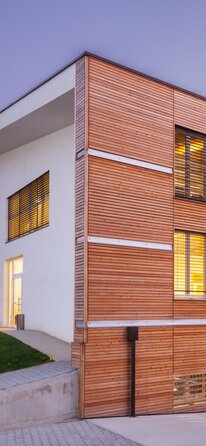 A three-storey building at dusk, clad in horizontal wooden slats.  | © Davide Cornacchini