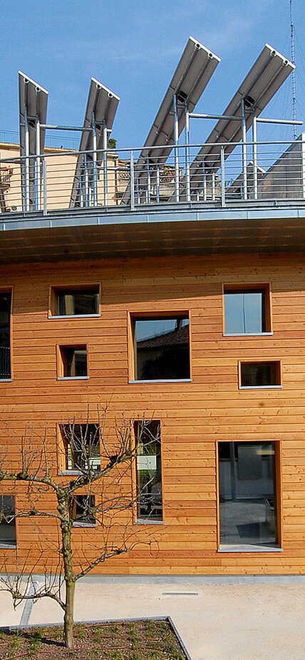 Facciata di un edificio a due piani con facciata in legno e finestre di varie dimensioni disposte irregolarmente | © LignoAlp