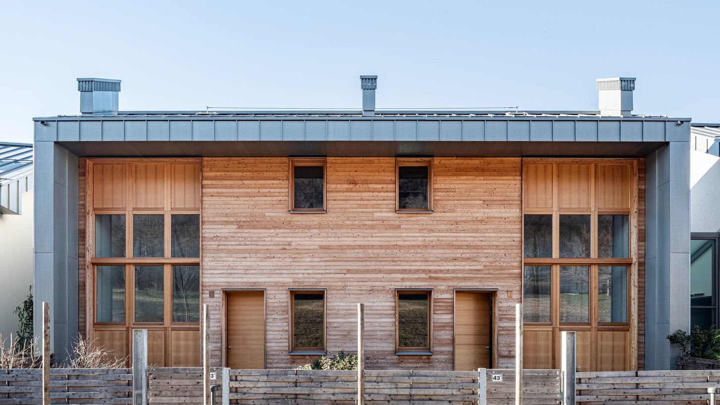 Un edificio residenziale con facciata in legno di larice e zinco titanio, con una recinzione in legno in primo piano | © Andrea Ceriani