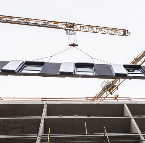 Ein großes Wandelement hängt an einem Baukran | © Regina Sedlmayer