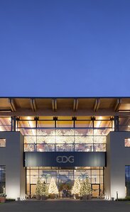 Ein großes Gebäudes in der Abenddämmerung, die Fassaden sind verputzt und haben große Fensterflächen, die Überdachung aus Holz hat einen großen Überstand | © Marco Zanta