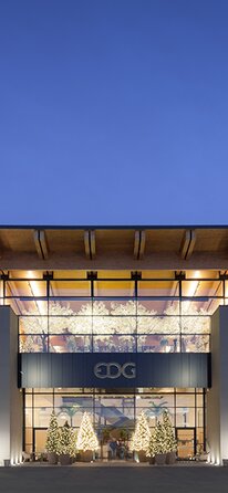 Un grande edificio all'imbrunire, le facciate sono intonacate e presentano ampie finestre, la copertura in legno ha un grande sporto | © Marco Zanta