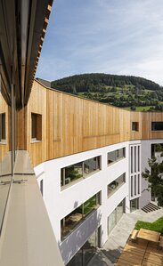 Edificio scolastico, ai tre piani seminterrati intonacati si aggiunge un quarto piano con rivestimenti in legno di larice. | © Samuel Holzner
