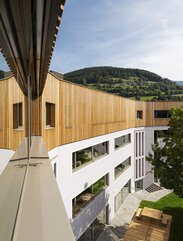A school building, on top of the three plastered basement floors there is a fourth floor with a cladding of larch wood | © Samuel Holzner