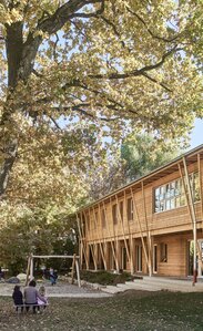 Un giardino con un grande albero e un edificio a due piani con un rivestimento in larice sulla facciata | © Kurt Hörbst