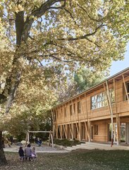 A garden with a large tree and a two-storey building with larch cladding on the façade | © Kurt Hörbst