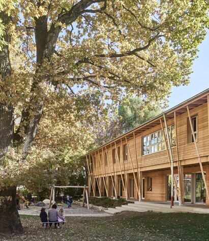 A garden with a large tree and a two-storey building with larch cladding on the façade | © Kurt Hörbst