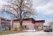 Fassade einer Schule in Holzbauweise mit vorvergrauter Fassadenschalung und roter Fassadenbahn | © Florian Holzherr