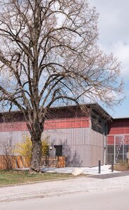 Fassade einer Schule in Holzbauweise mit vorvergrauter Fassadenschalung und roter Fassadenbahn | © Florian Holzherr