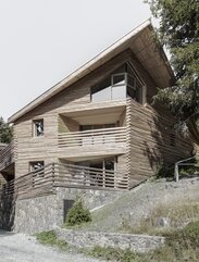 Ein Gebäude mit einem Sockel aus Naturstein und einer Fassadenverkleidung aus geviertelten Baumstämmen | © Gustav Willeit