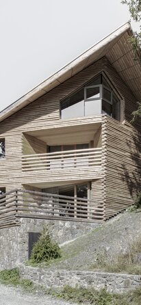 Un edificio con uno zoccolo in pietra naturale e un rivestimento della facciata in tronchi d'albero tagliati in quattro | © Gustav Willeit