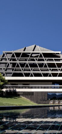 A large building with a façade of dark wood, in the foreground an outdoor swimming pool | © Florian Andergassen