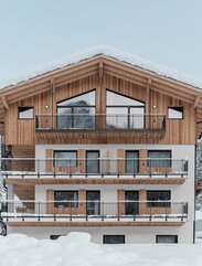 Un edificio circondato dalla neve; un nuovo piano con rivestimento esterno in legno si erge su tre piani intonacati | © Davide Perbellini