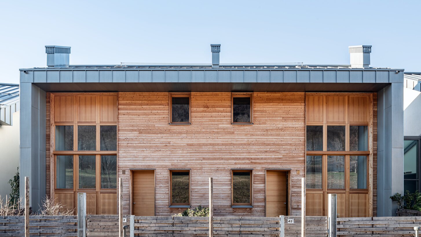 Un edificio residenziale con facciata in legno di larice e zinco titanio, con una recinzione in legno in primo piano | © Andrea Ceriani