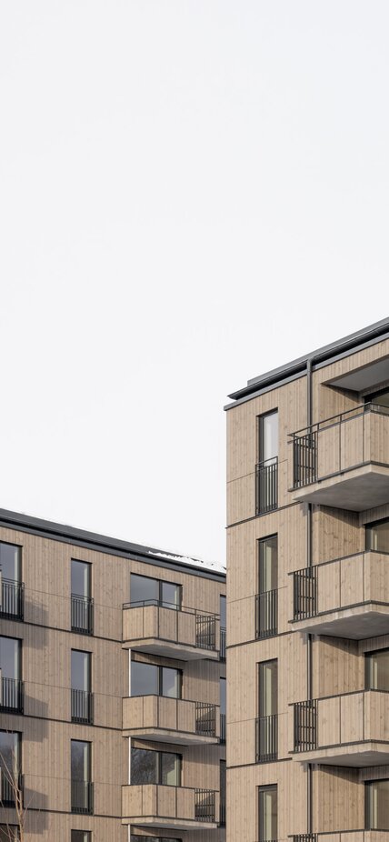 Teilansicht der Fassaden von zwei großen Wohngebäuden aus Holz | © Florian Holzherr