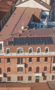 Un edificio storico a cui è stato aggiunto un piano aggiuntivo. L'ampliamento è rivestito esternamente con lamiera color rame e sul tetto sono installati moduli fotovoltaici.