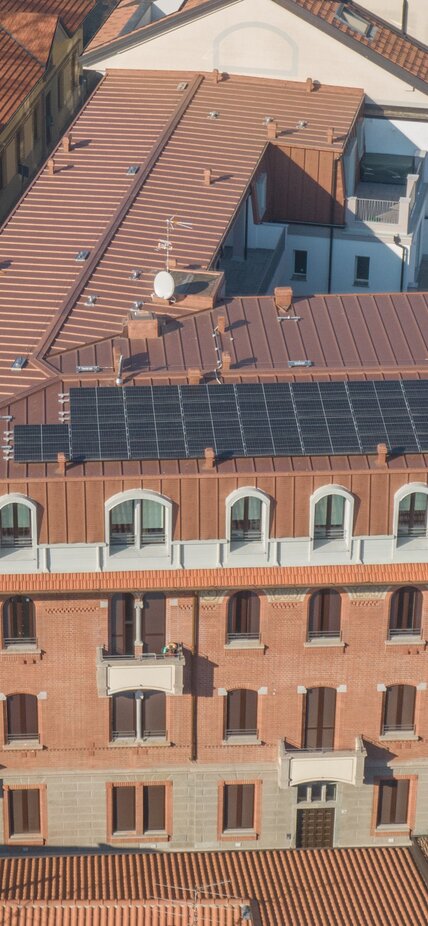 A historic building on which an additional storey has been added. The extension is clad on the outside with copper-coloured sheet metal and photovoltaic modules are installed on the roof