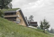 n a green meadow stands a new house with walls made of natural wood and a green roof | © Gustav Willeit