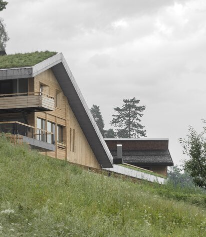 In einer grünen Wiese steht ein neues Haus mit Wänden aus naturbelassenem Holz und einem begrünten Dach aus Beton | © Gustav Willeit