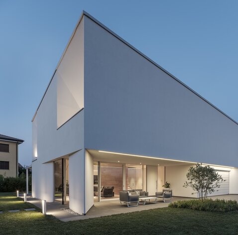 Eine moderne Villa mit verputzter Außenfassade und großen Fensteröffnung | © Davide Perbellini