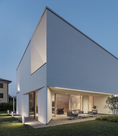 Eine moderne Villa mit verputzter Außenfassade und großen Fensteröffnung | © Davide Perbellini