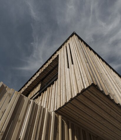 Ein Gebäude, das an der Außenfassade mit einer Schalung aus Lärchenholz-Leisten verkleidet ist | © Mariano Dallago